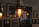 A cozy living room softly lit by a warm industrial cage pendant light hanging above a wooden table.