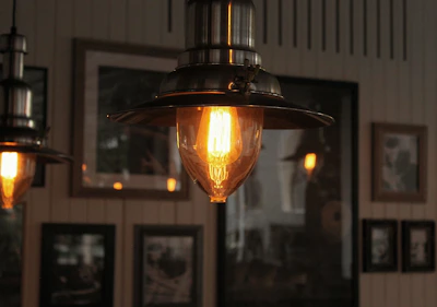 A warm-lit industrial cage pendant hanging above a cozy rustic wooden table.