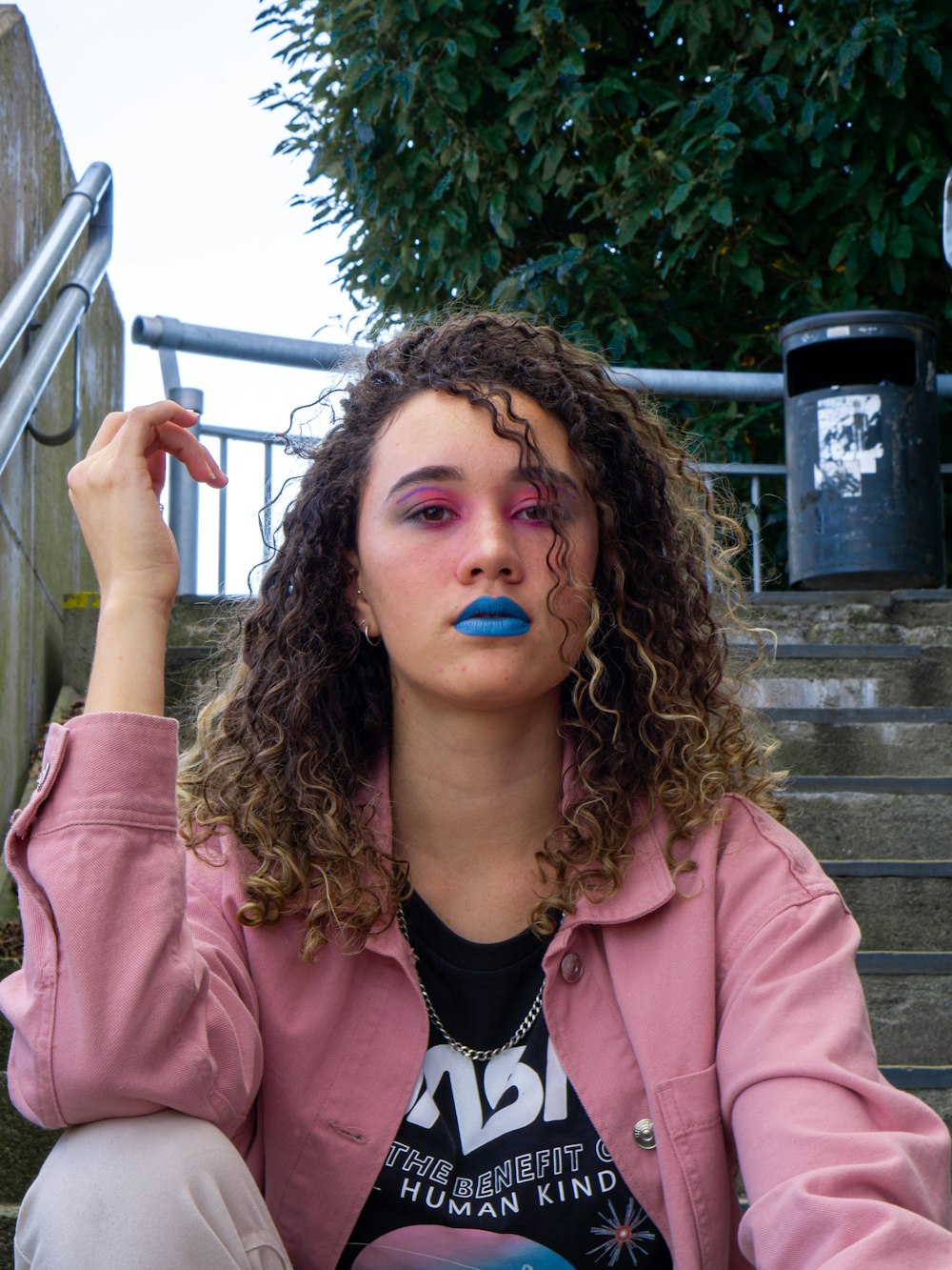 woman in pink jacket with blue nail polish