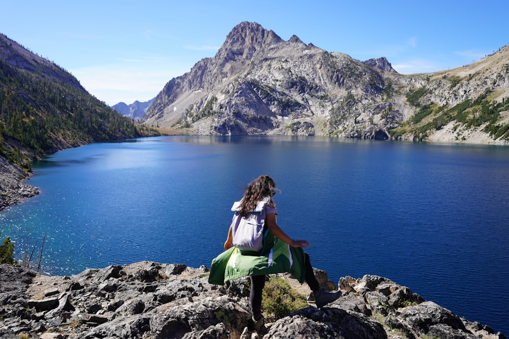 woman in black tank top sitting on green chair near body of water during daytime