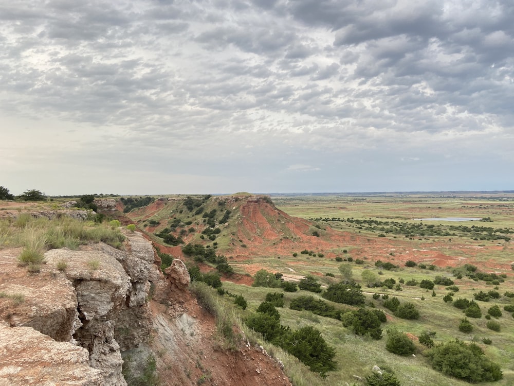 Campo de hierba marrón y verde bajo nubes blancas y cielo azul durante el día