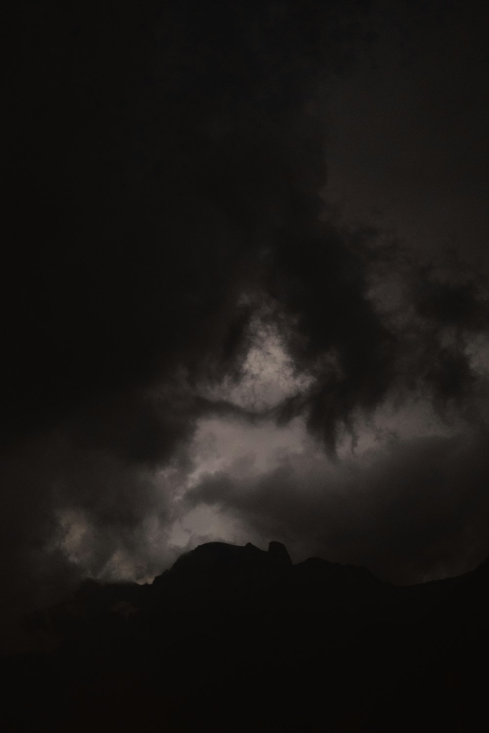 grayscale photo of mountain under cloudy sky