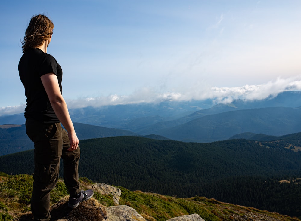 man in black t-shirt standing on rock formation during daytime