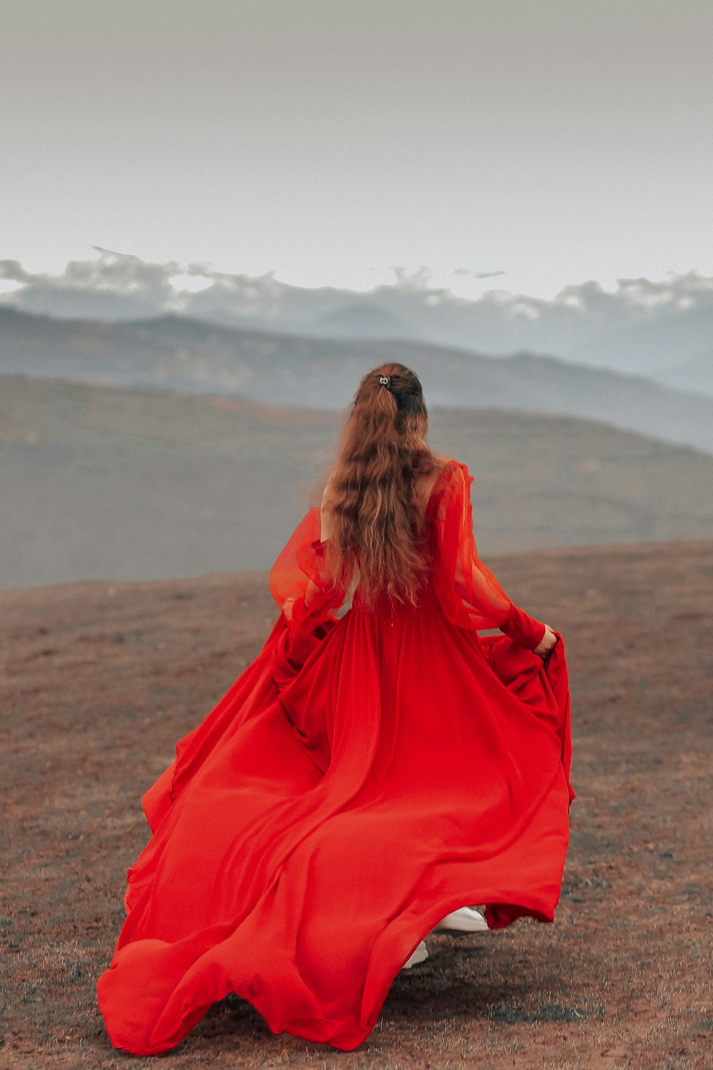 woman in red dress sitting on brown field during daytime
