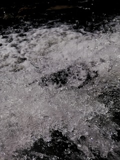 Turbulent water splashes chaotically with white foam and glistening droplets against a dark backdrop.