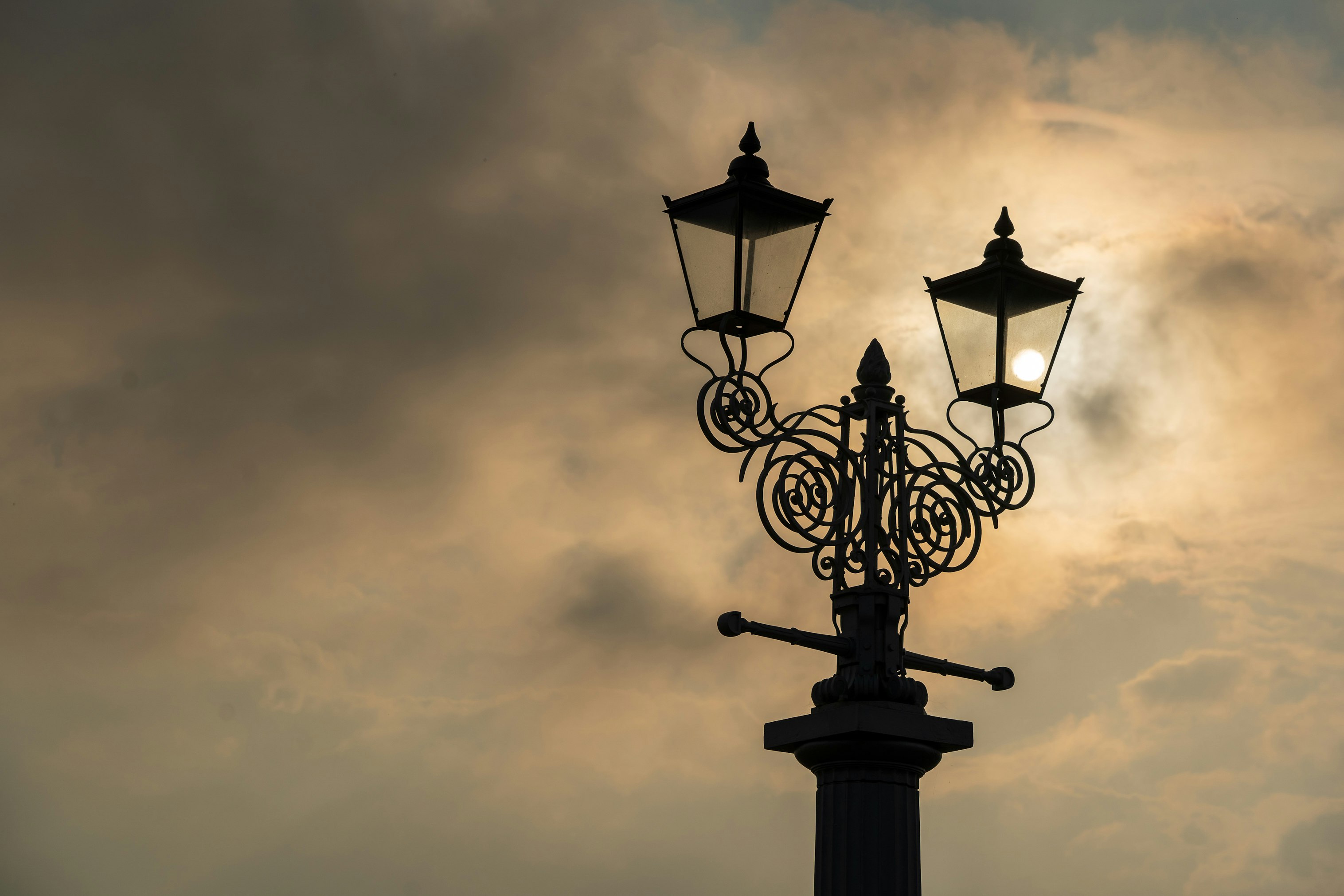 black metal street light under gray clouds