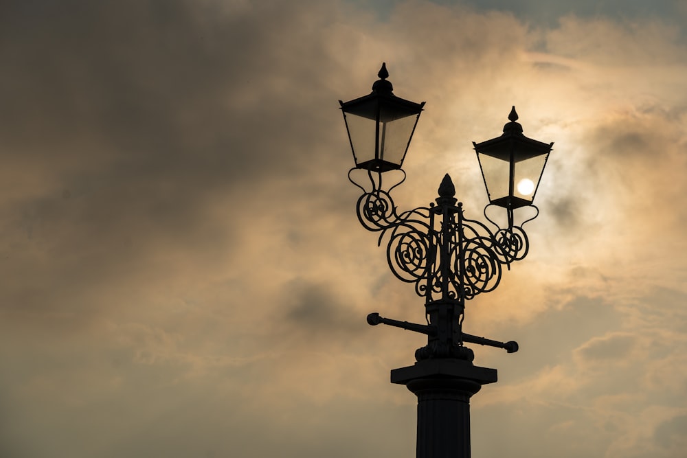 black metal street light under gray clouds