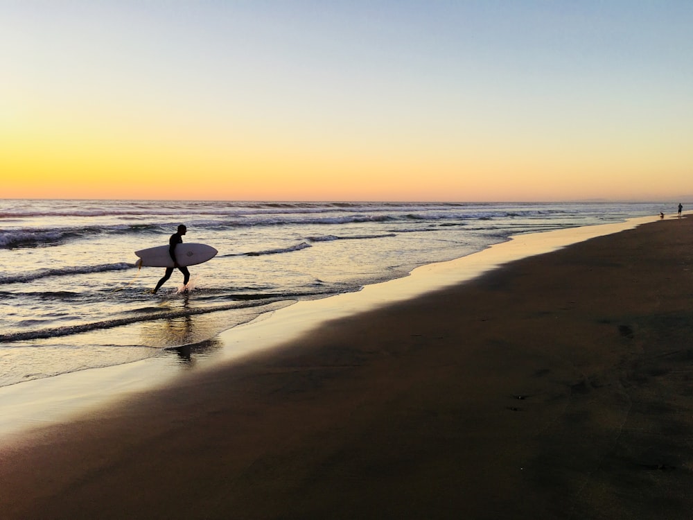 silhouette dell'uomo che cammina sulla spiaggia durante il tramonto