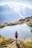 A smiling hiker standing on a mountain summit with panoramic alpine views in the background.