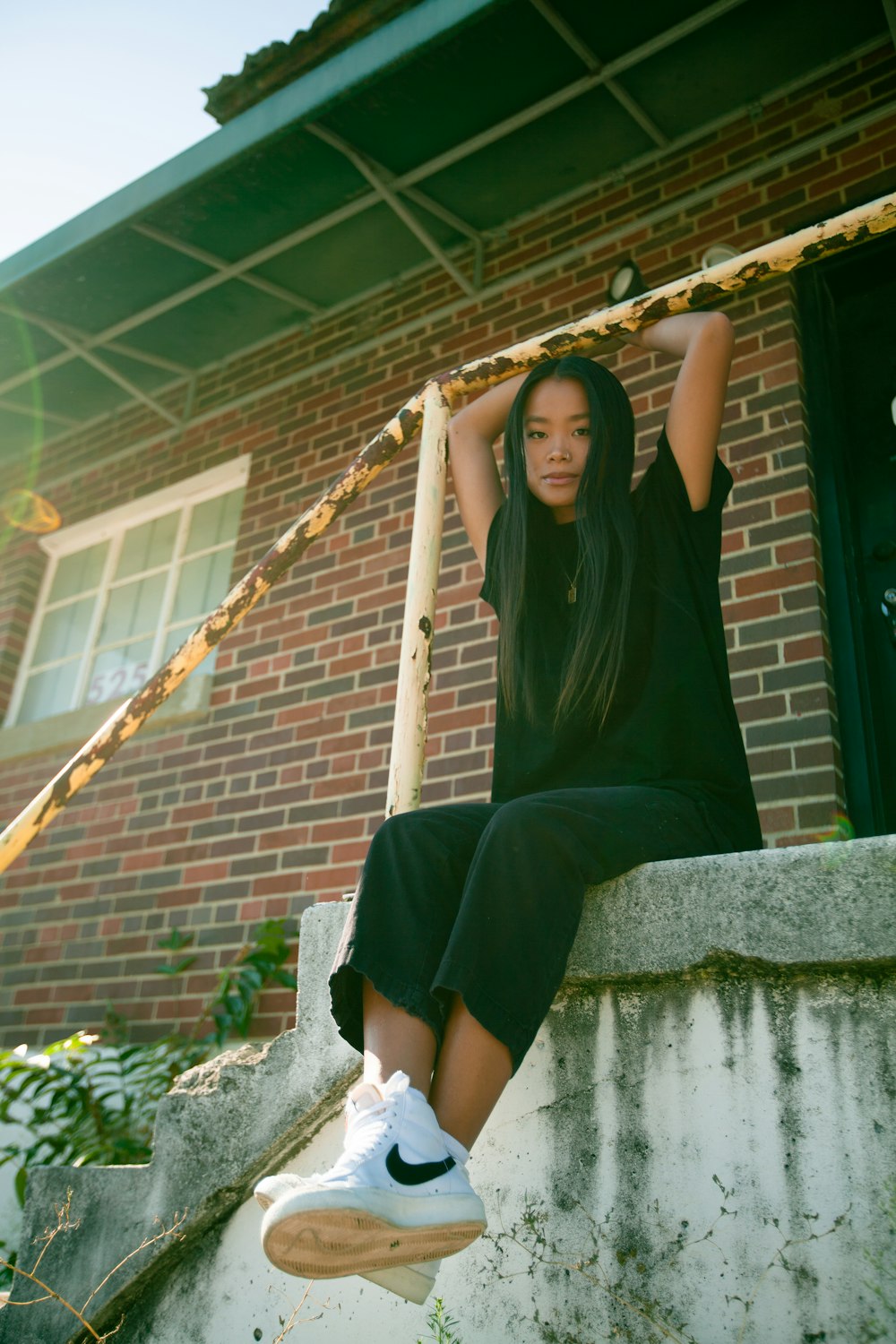 woman in black long sleeve dress sitting on concrete wall during daytime