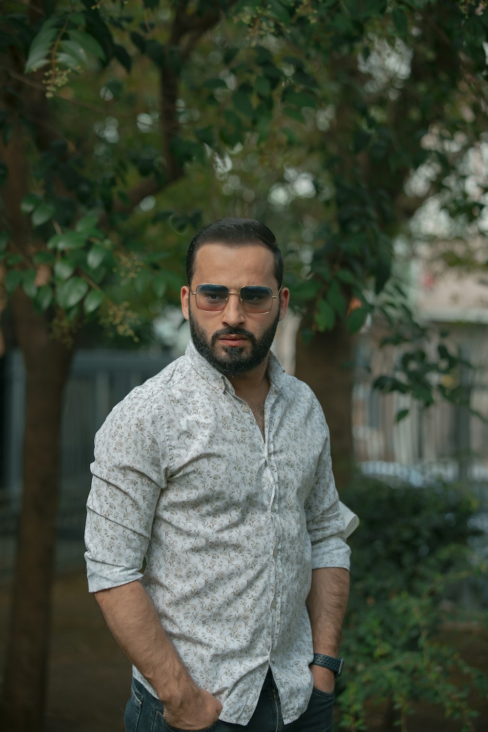 Hombre con camisa gris abotonada con gafas de sol negras