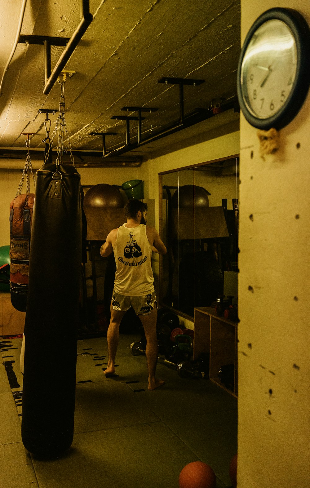 man in white crew neck t-shirt and black shorts standing beside white wall