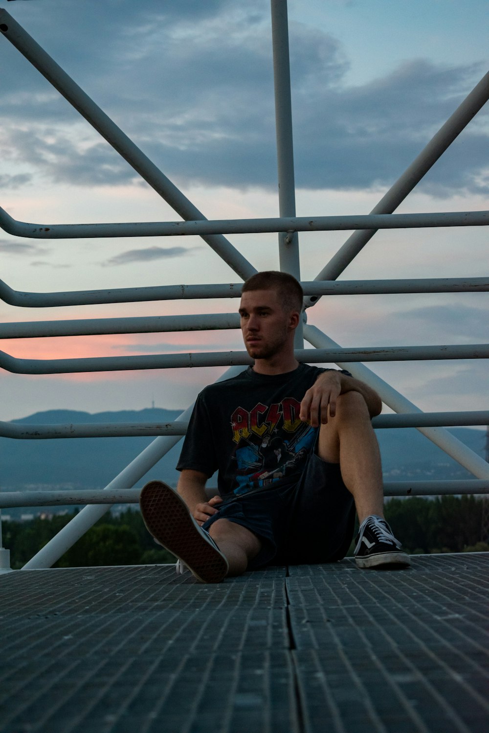 man in black crew neck t-shirt sitting on white metal railings during daytime