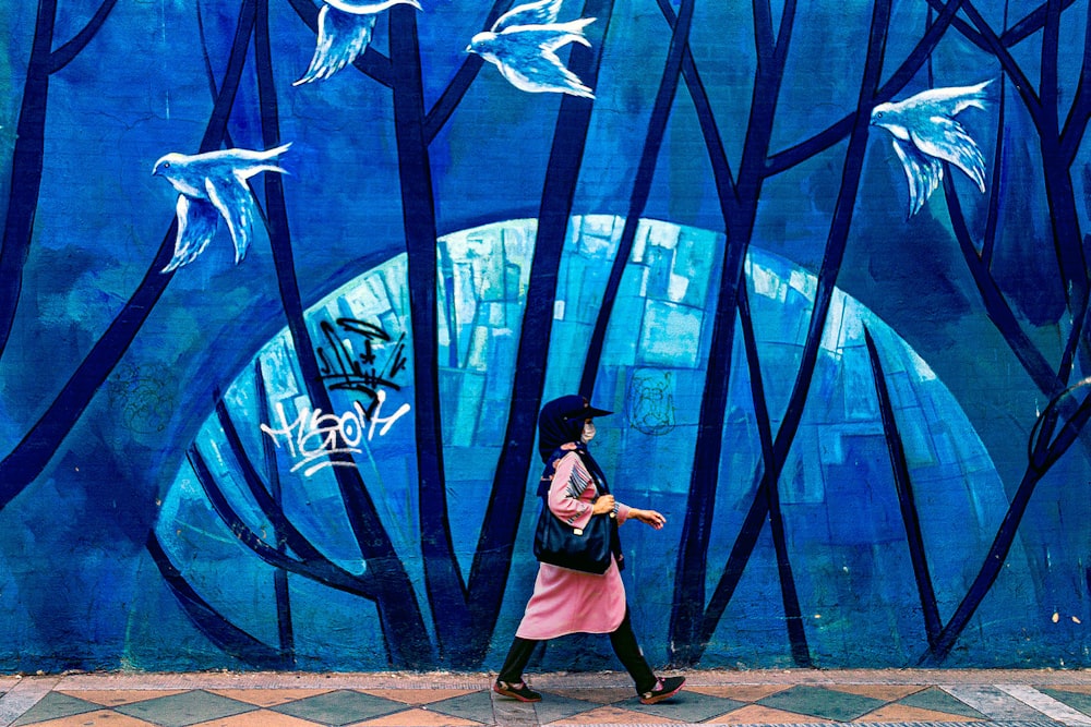 woman in black dress standing beside blue and white wall