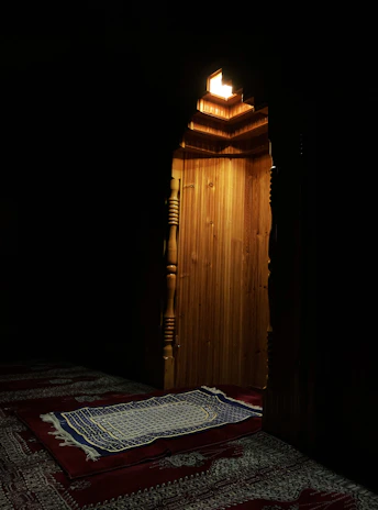 Cozy prayer room adorned with a soft, detailed carpet and Arabic ornaments illuminated by lantern light