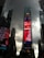 Tall skyscrapers under a cloudy sky surround a vibrant digital billboard displaying various advertisements in a bustling urban setting.