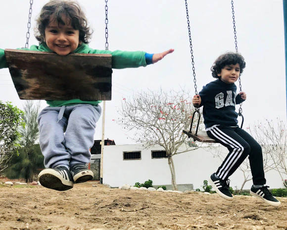 Kids jumping and playing in a park, each wearing different bright hoodies and shorts.