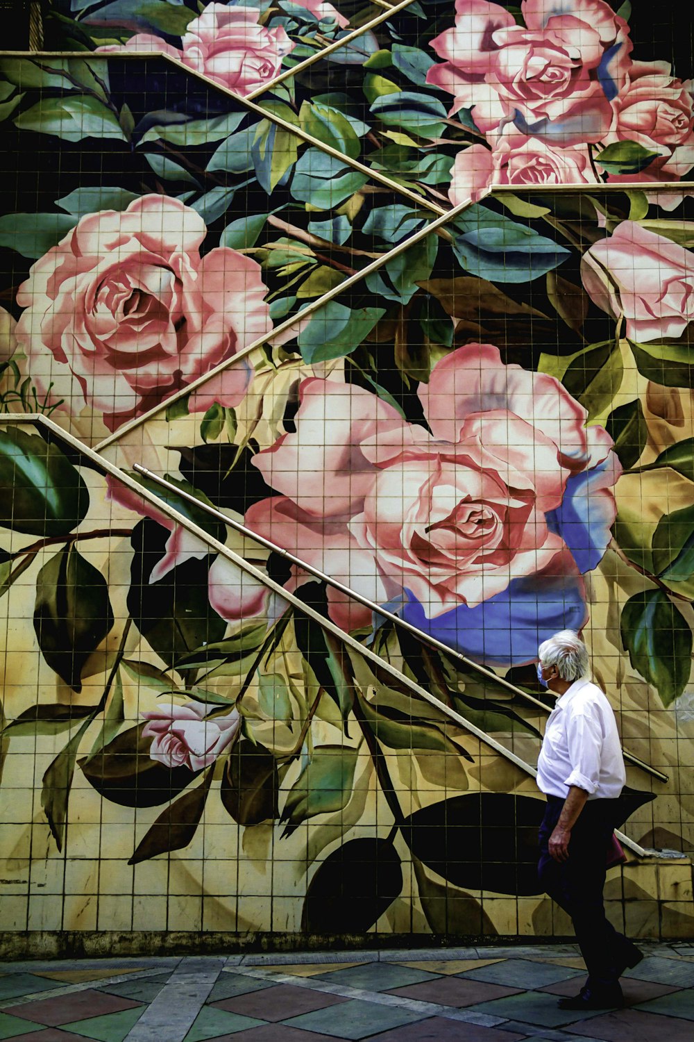 woman in white long sleeve shirt standing beside pink rose flower painting