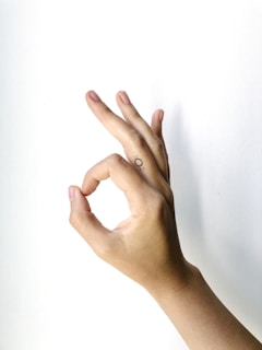 a female right hand making okay sign with thumb and index against a white background
