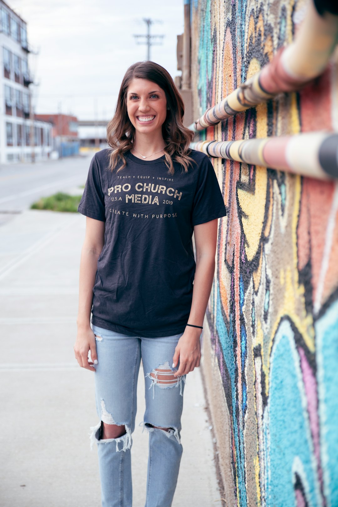 woman in black crew neck t-shirt and blue denim jeans standing beside wall with graffiti
