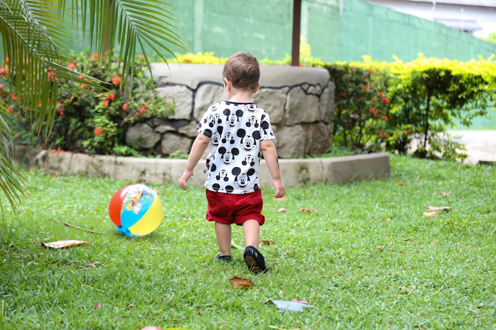 boy in white and black crew neck t-shirt and red shorts playing with ball on on on on on