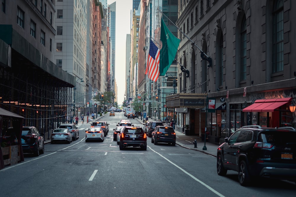 cars on road between high rise buildings during daytime