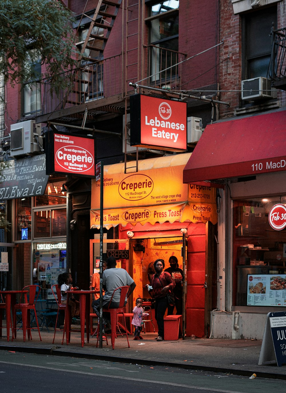 people sitting on red chairs near store during daytime