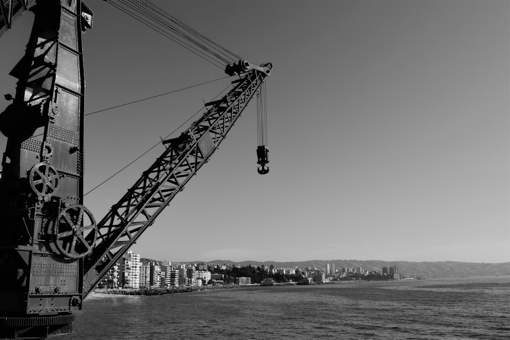 grayscale photo of crane near city buildings