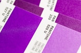 Close-up view of several Pantone color swatches, primarily in shades of purple and violet. The swatches are arranged diagonally, with some numbers and codes visible such as 528 U and 527 U.