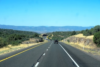 A KDH vehicle driving smoothly on a highway surrounded by green hills under a clear blue sky.