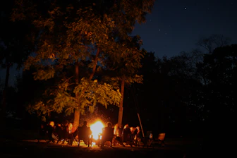 A local guide sharing stories with travelers around a campfire under starry skies.