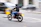 A confident man on a motorcycle helmet, riding through city streets with a focused expression.