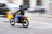 A confident man on a motorcycle helmet, riding through city streets with a focused expression.