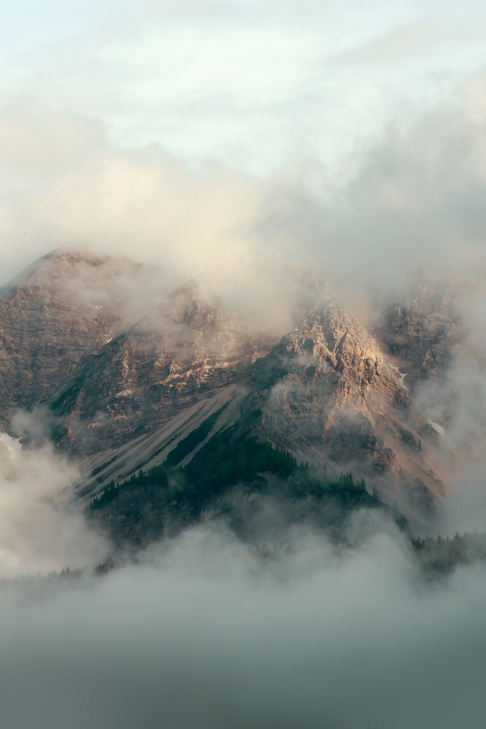 白い雲で覆われた茶色と灰色の山