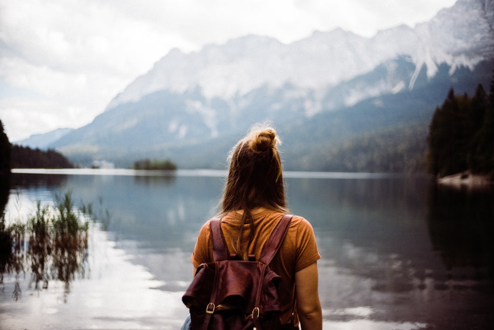 woman in pink shirt standing near lake during daytime