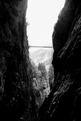 grayscale photo of bridge between rock formation