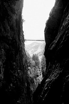 grayscale photo of bridge between rock formation