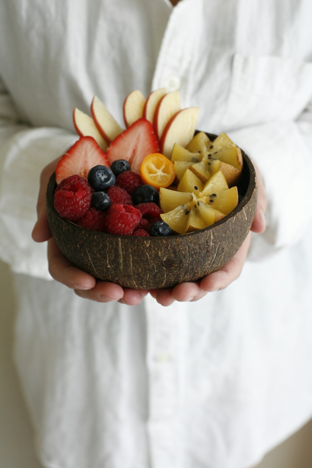 person holding brown round cake with fruits