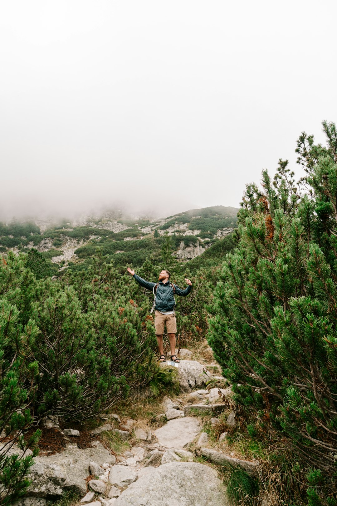 man in black jacket standing on rock formation during daytime