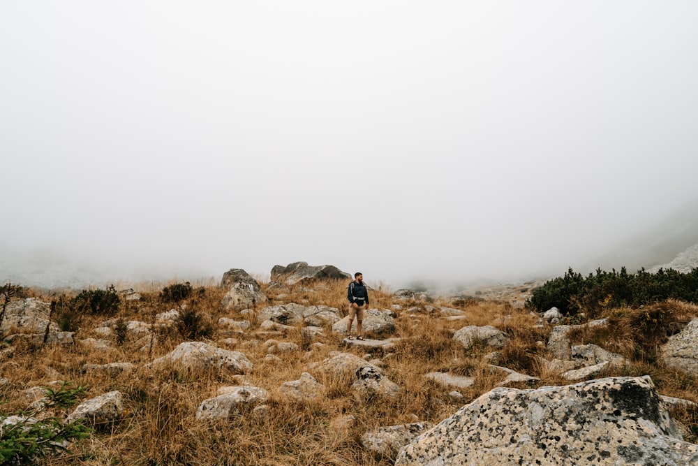 person in black jacket and black pants walking on rocky hill during daytime