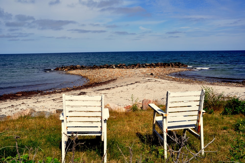 昼間のビーチにある白い木製の椅子