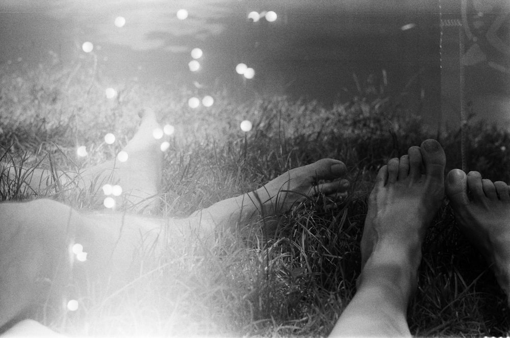 grayscale photo of persons feet on grass field