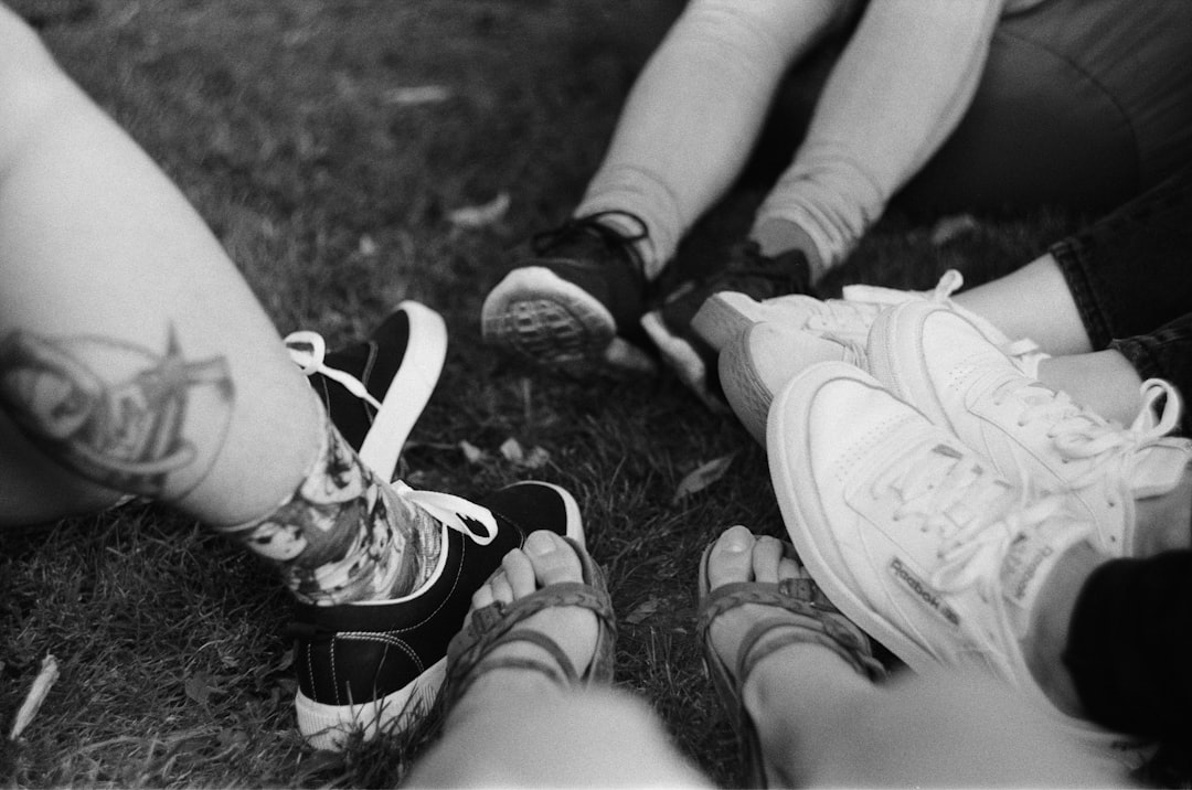 grayscale photo of person wearing black and white sneakers