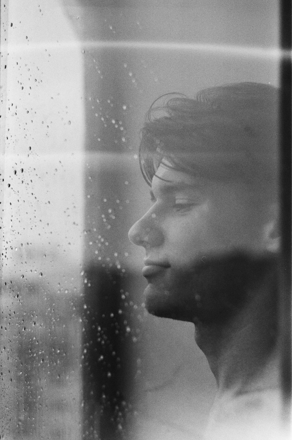 grayscale photo of woman looking at glass window