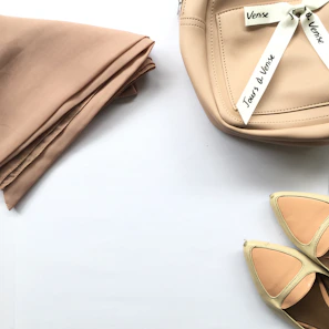 A collection of hijabs in beige and cream tones, neatly folded and styled on a smooth surface.