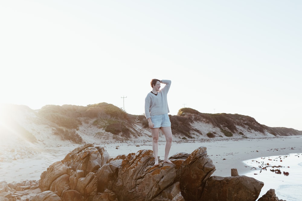 man in white dress shirt standing on brown rock formation during daytime