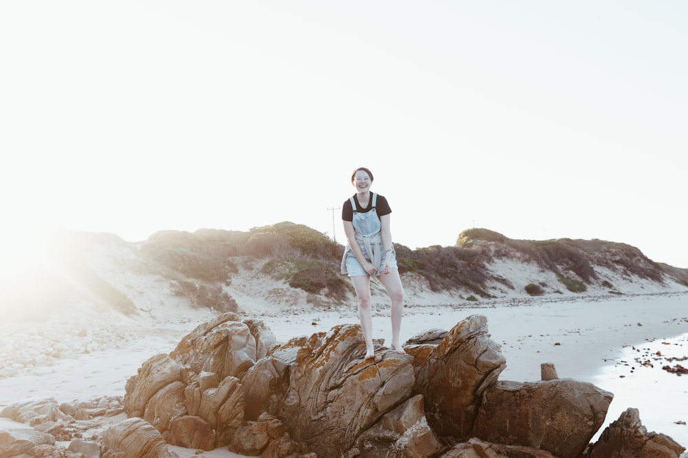 a person standing on a rock on a beach