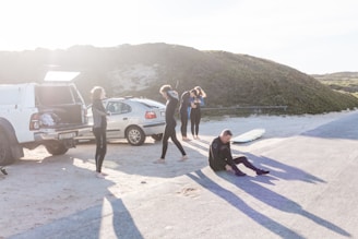 A group of diving instructors in wetsuits preparing gear on a sunny beach.