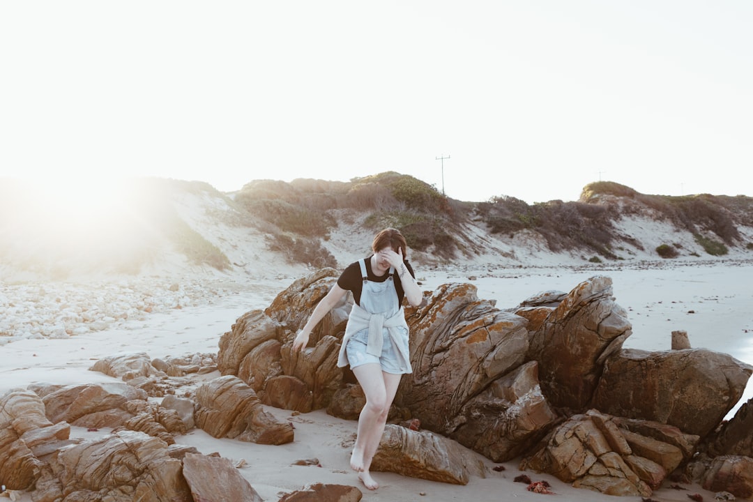 woman in white long sleeve shirt standing on brown rock formation during daytime