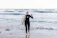 A smiling instructor helping a young surfer catch a wave at Les Grenettes beach.